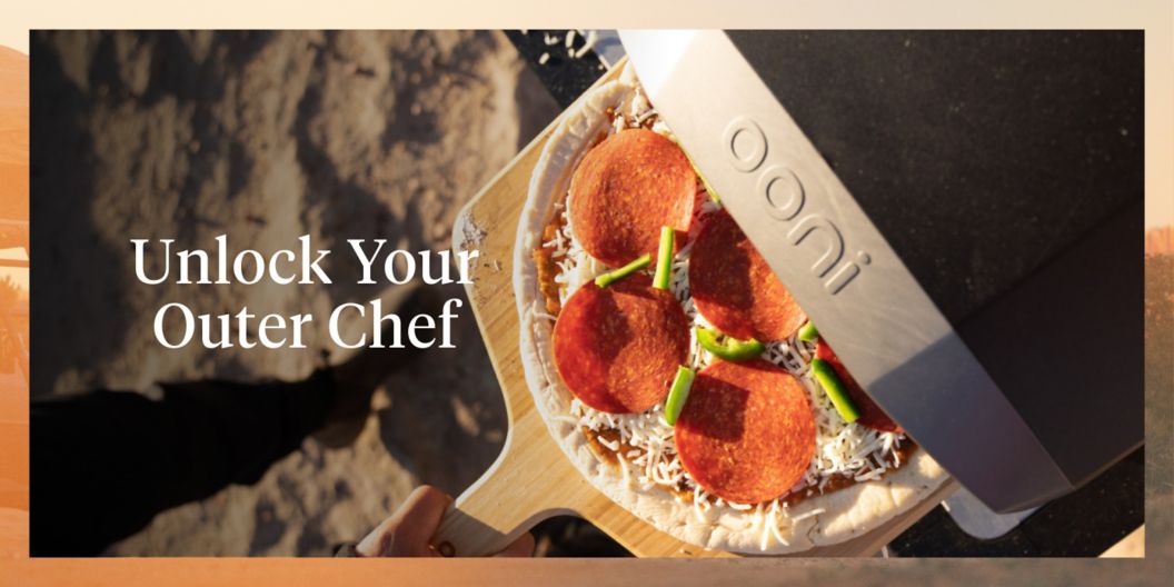 A peperino-covered pizza is halfway in an Ooni pizza oven. “Unlock Your Outer Chef” is in large white letters over the image. 